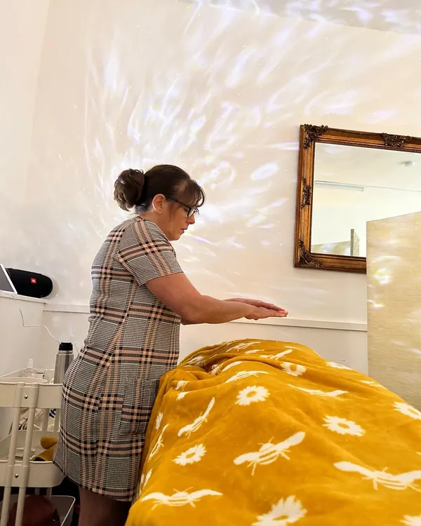 Nicky giving reiki to a client resting under a yellow blanket