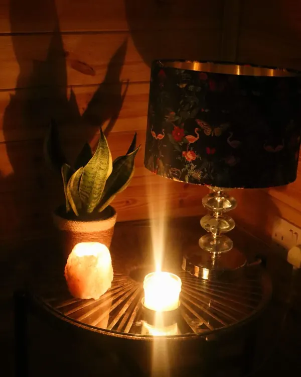 A salt lamp, a candle and a plant glowing in the garden room in the evening