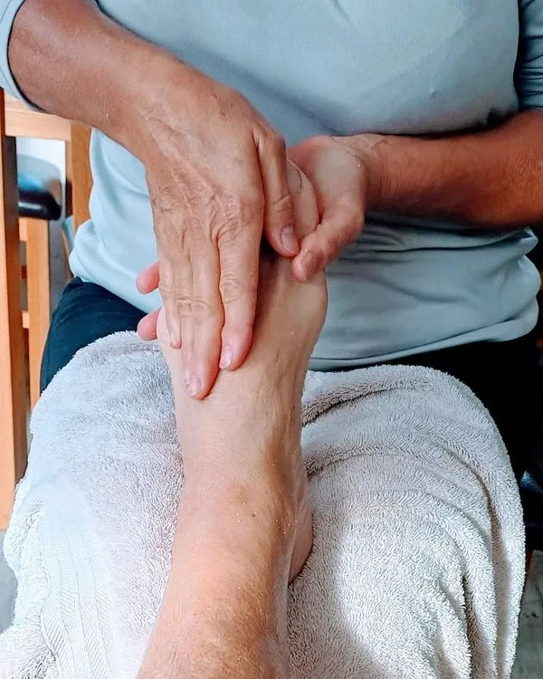 Hands massaging a client’s foot, resting on a towel